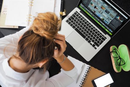 woman holding her head at computer