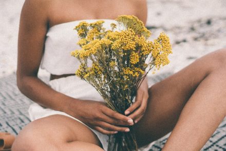 woman in white shorts holding yellow flowers