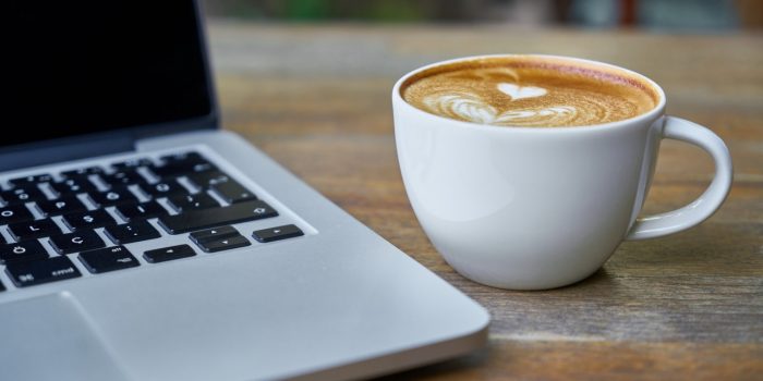 Teacup of Latte Beside Macbook Pro
