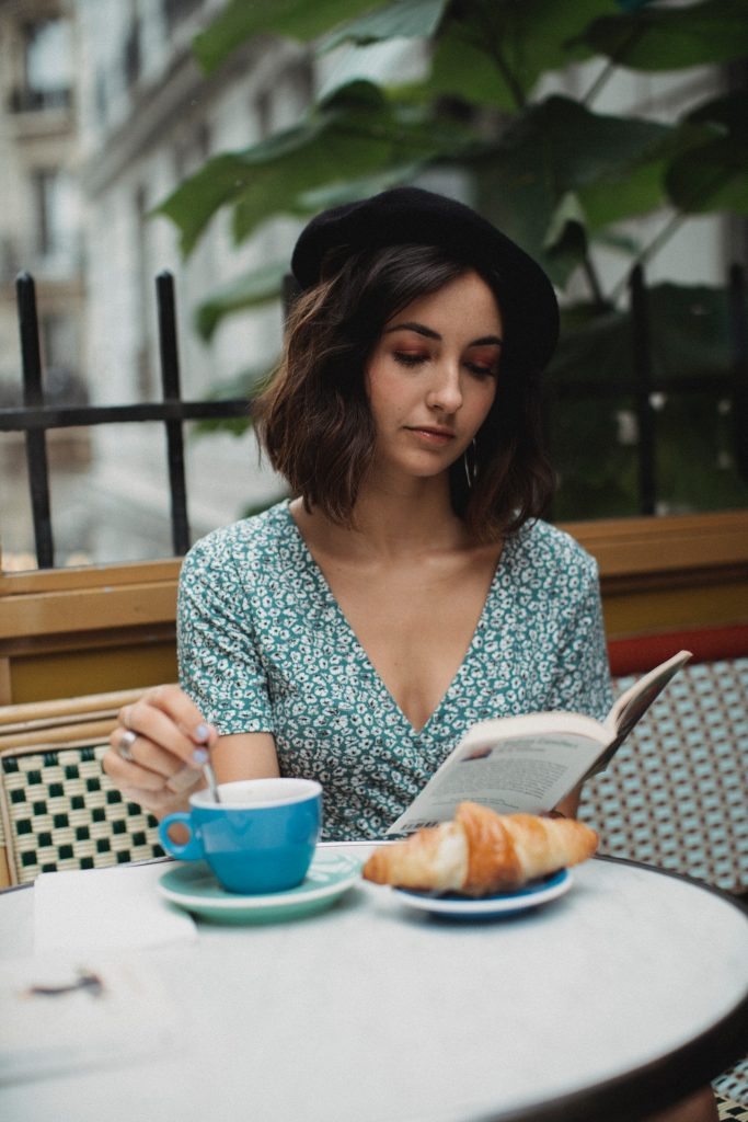Woman Wearing Beret And Reading a Book in a French Cafe

