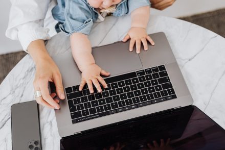 Woman using laptop while holding baby